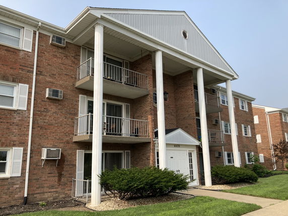 Front view of a multi-story brick apartment building with balconies and large white columns.