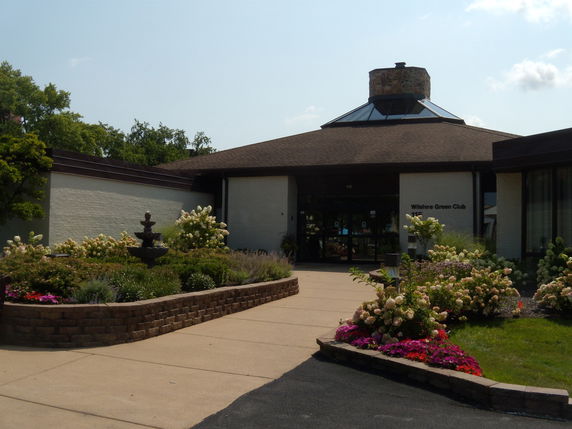 Front view of a club building with a sloped roof and entrance pathway.