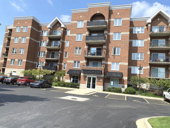 Front view of a multi-story brick apartment building with balconies.