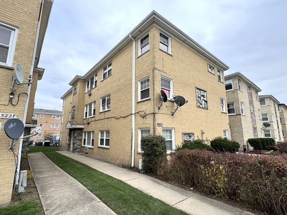Front view of a multi-story brick building with satellite dishes attached.