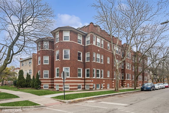 Front view of a red brick multi-story apartment building.