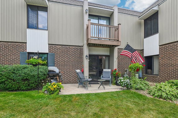 Front view of a brick and siding two-story house with a small patio area.