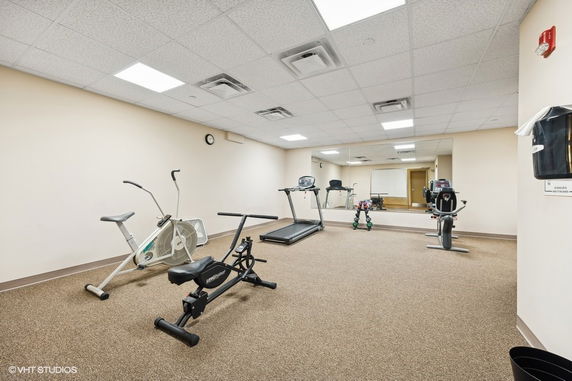 Indoor gym with exercise equipment and a large mirror on the wall.