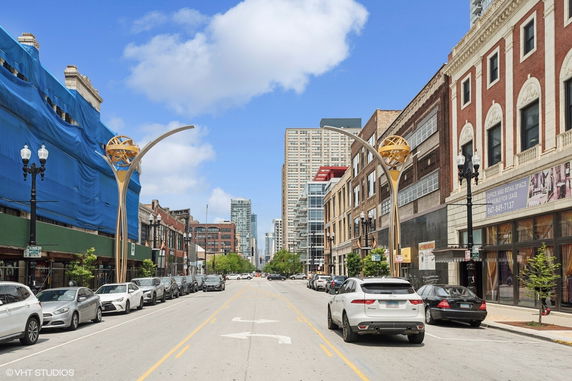 Street view with buildings, vehicles, and decorative street lamps.