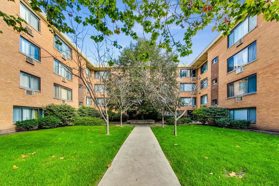 Front view of a multi-story brick building with large windows and air conditioning units.