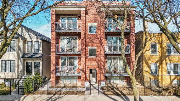 Front view of a brick multi-story residential building with balconies.