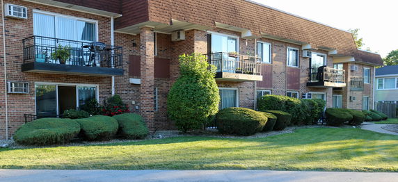 Front view of a multi-story brick apartment building with balconies.