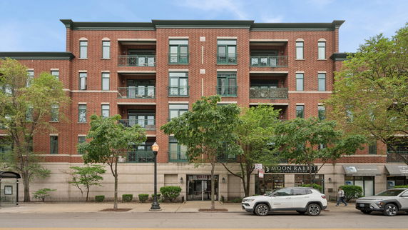 Front view of a multi-story brick building with multiple balconies and street-level shops.
