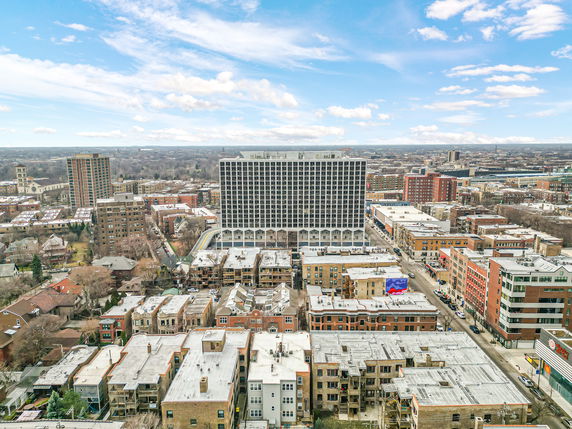 Panoramic view of a cityscape with multiple residential and commercial buildings under a blue sky.