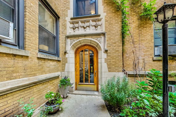Front view of a building entrance with arched wooden door and brick facade.