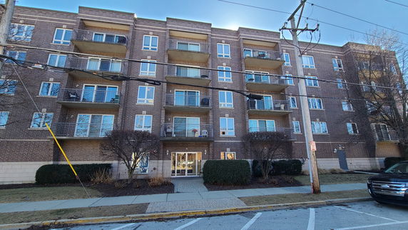 Front view of a multi-story brick apartment building with balconies.