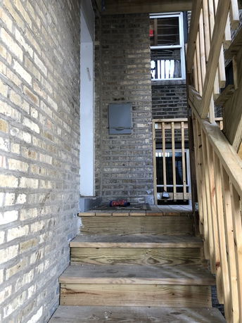 Front entrance view with brick exterior and wooden stairs.