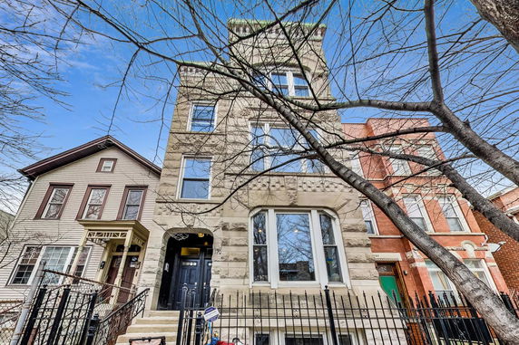 Front view of a multi-story building with a stone facade and tall windows.