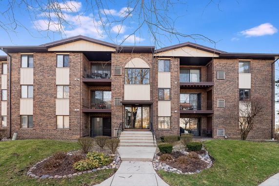 Front view of a multi-story brick apartment building with balconies.