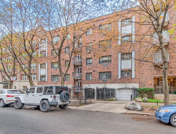 Front view of a multi-story brick building with balconies and a garage.