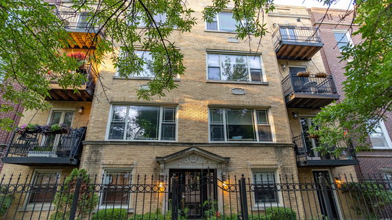 Front view of a multi-story brick apartment building with balconies.