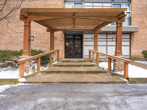 Front view of a building with a wooden pergola and brick exterior.