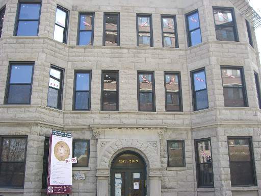 Front view of a multi-story stone building with large windows.