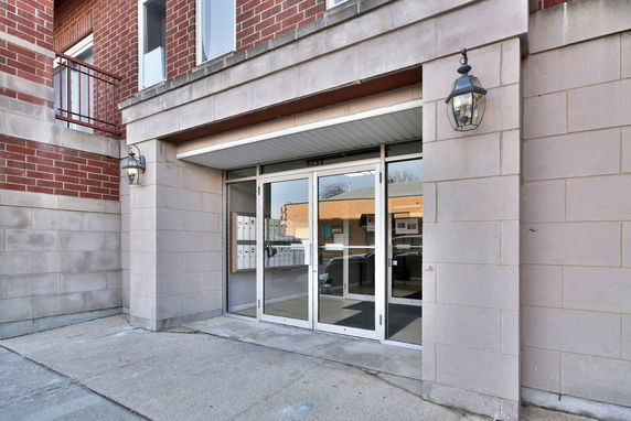 Front view of a building entrance with glass doors and mailboxes.