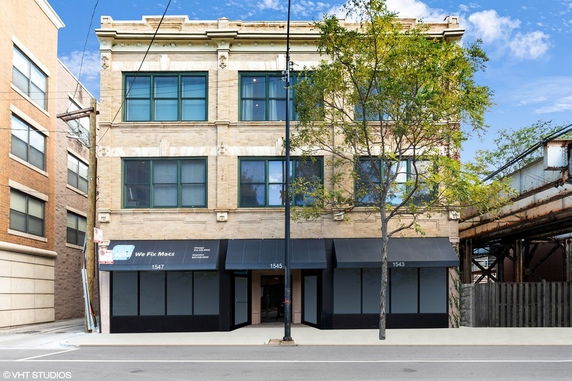Front view of a four-story commercial building with large windows and awnings on the ground floor.