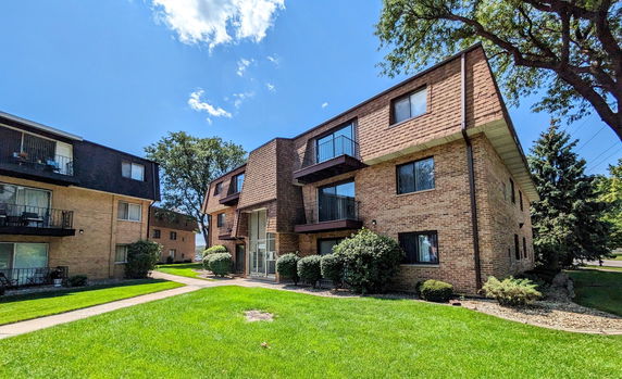 Front view of a multi-story brick apartment building with balconies.