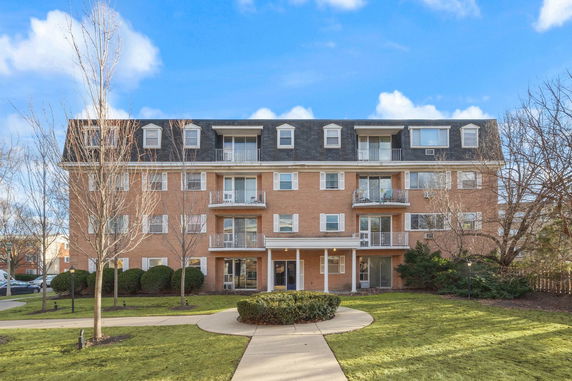 Front view of a four-story brick apartment building with balconies.