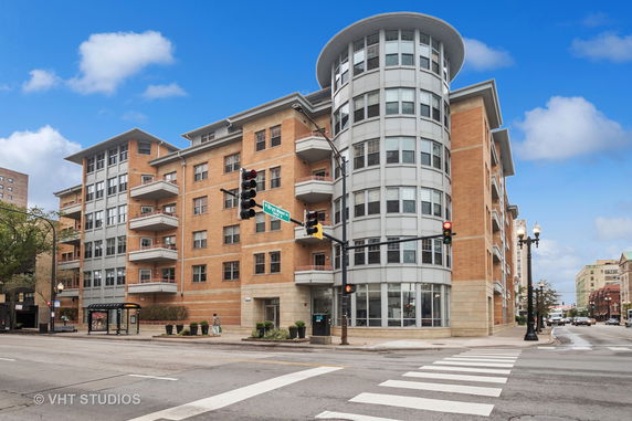 Front view of a multi-story building with a rounded corner and multiple balconies.