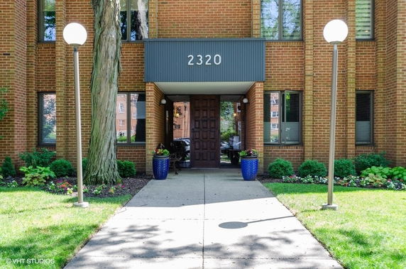 Front view of a brick apartment building entrance with the number 2320 above the door.