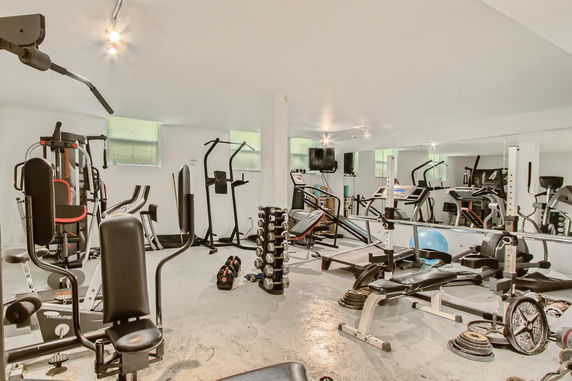 Indoor gym area equipped with various exercise machines and weights.