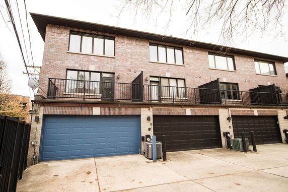 Front view of a three-story building with garages on the ground floor.