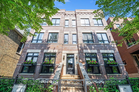 Front view of a multi-story brick building with a central entrance and balconies.