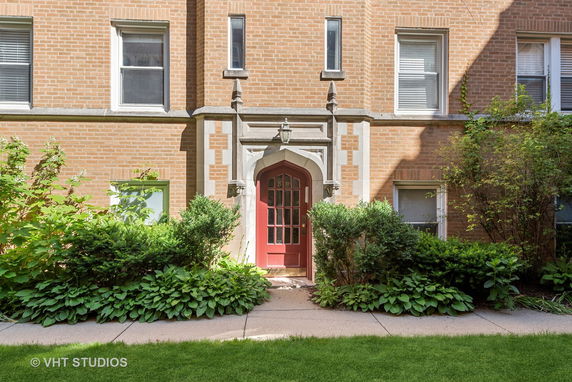 Front view of a building entrance with red door and brick facade.
