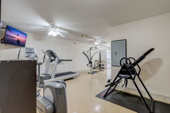 Indoor gym area with exercise equipment and a wall-mounted TV.