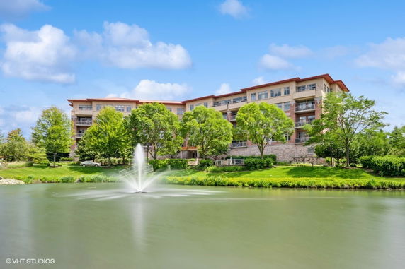 Front view of a multi-story building with balconies and a fountain in front.