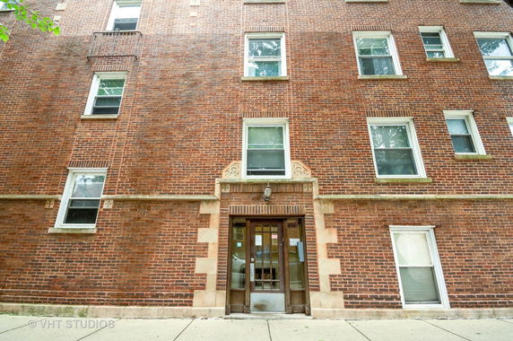 Front view of a multi-story brick building with several windows.