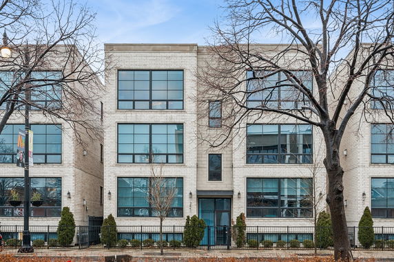 Front view of a modern multi-story building with large windows and brick facade.