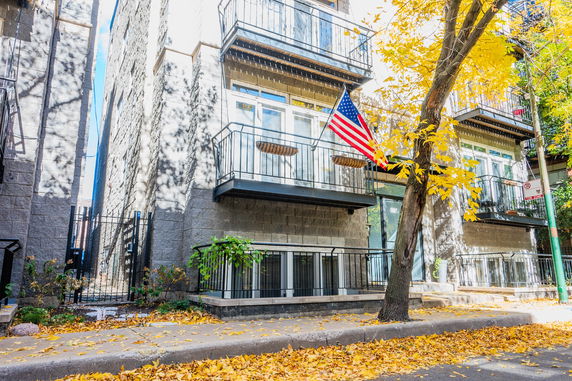 Front view of a multi-story building with balconies and American flag.