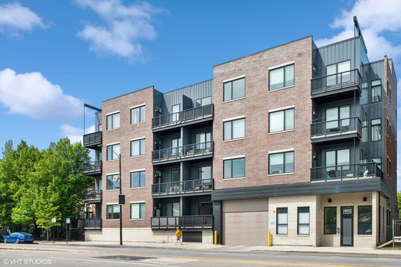 Front view of a modern multi-story apartment building with balconies.