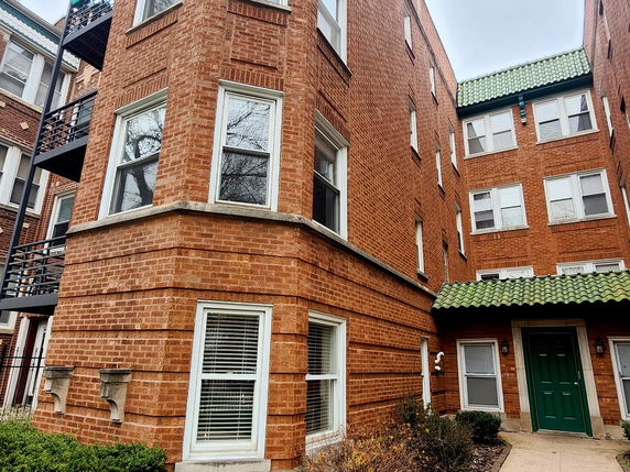 Front view of a multi-story brick building with a green door.