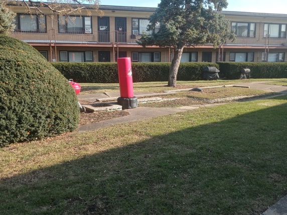 View of a two-story building with multiple apartments and a small outdoor fitness area.