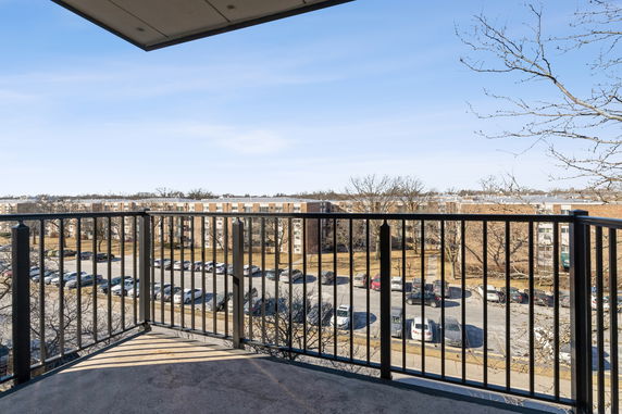 View from a balcony overlooking a residential area and parking lot.