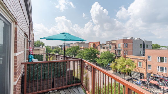 View of surrounding neighborhood from a balcony with umbrella shading.