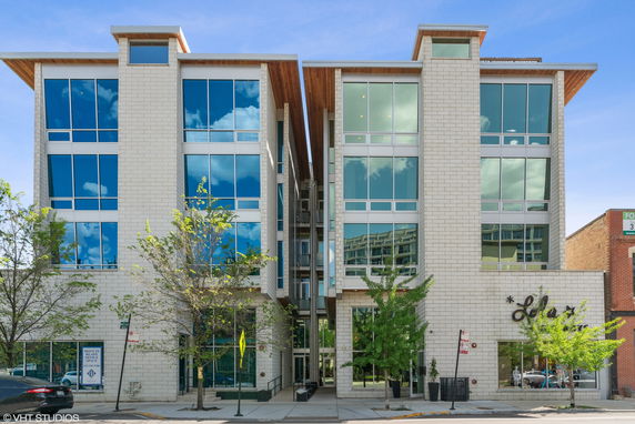 Front view of a modern multi-story building with large glass windows and a central entrance.