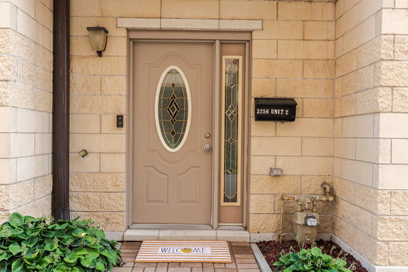 Front view of a building entrance with a door, welcome mat, and a mailbox labeled Unit 2.