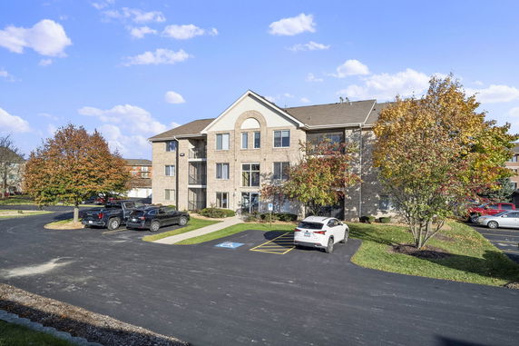 Front view of a multi-story apartment building with parking spaces in front.