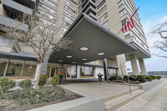 Front view of a high-rise building with a covered entrance and glass doors.