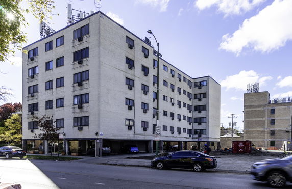 Front view of a multi-story residential building with a parking area beneath.