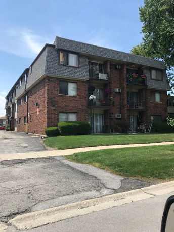 Front view of a multi-story brick apartment building with balconies.