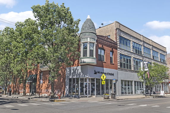 Front view of a multi-story commercial building on a street corner with large windows.