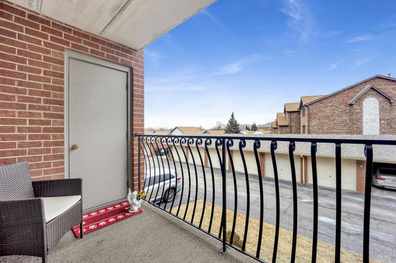 Balcony view showing surrounding residential buildings and parked cars.